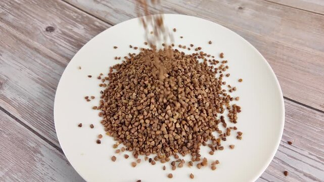 Falling buckwheat groats forming pile on wooden table