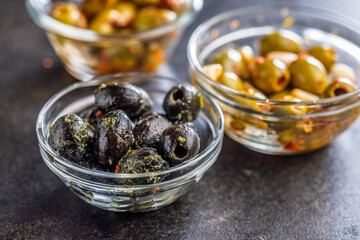 Tapas. Flavored pickled olives in bowl on black table.