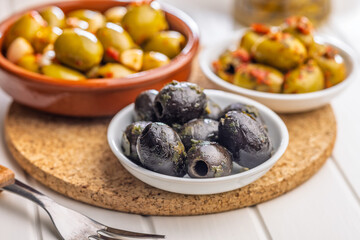 Tapas. Flavored pickled olives in bowl on white table.