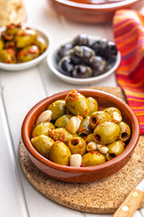 Tapas. Flavored pickled olives in bowl on white table.