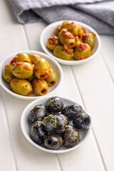 Tapas. Flavored pickled olives in bowl on white table.