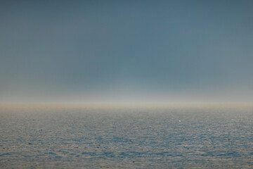 Fototapeta premium Endless ocean horizon sparkles under golden sunlight, blending into a deep blue sky. Calm waters shimmer gently, evoking a sense of peace and infinity.
