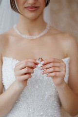 Bride holds wedding ring before ceremony in elegant bridal attire
