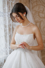 Bride preparing in elegant wedding gown by the window during soft natural light