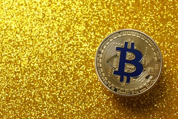 Top view of gold bitcoin coin on a shiny background, top view, space for text