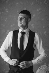 Smartly dressed man adjusting his vest in a well-lit indoor setting