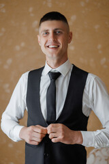 Man in formal attire adjusting vest in elegant setting with neutral background