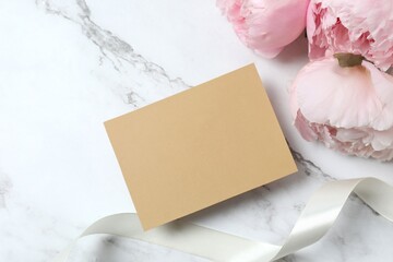Pink peonies with paper card, top view, space for text