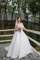 Bride poses in elegant gown with bouquet in serene forest setting during daytime