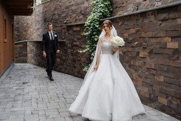 Bride walks down a charming pathway while groom approaches at a romantic wedding venue