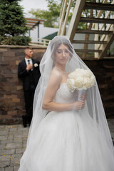 Beautiful bride in stunning wedding gown holding bouquet outdoors on special day