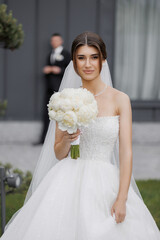 Beautiful bride holding bouquet stands confidently on her wedding day in a scenic outdoor setting