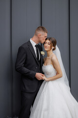 Couple celebrating their wedding in elegant attire against a stylish gray backdrop