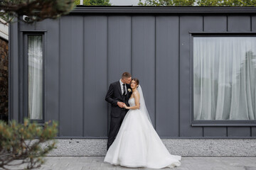 Couple in elegant attire share a romantic moment outside a modern building