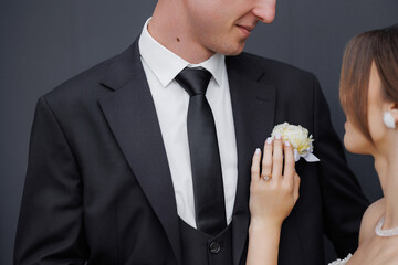 Groom adjusts flower on lapel during wedding ceremony preparations at elegant venue