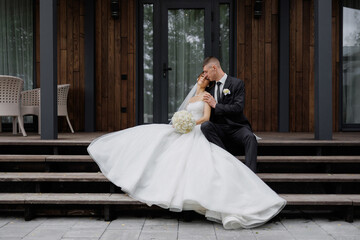 Bride and groom share an intimate moment on a wooden staircase at a wedding venue