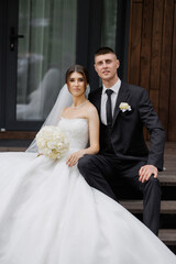 Couple sits on steps together, celebrating their wedding day in a rustic venue