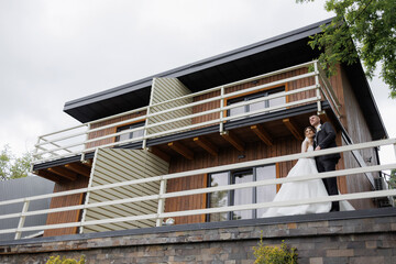 Couple celebrates love outside modern wooden house on their wedding day