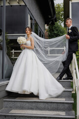 Couple celebrating their wedding day at a modern venue while the bride elegantly ascends the steps