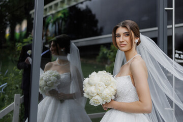 Bride poses with bouquet reflecting elegance in modern setting on her wedding day