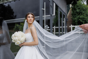 Bride enjoying outdoor moment at modern venue with flowers and flowing veil