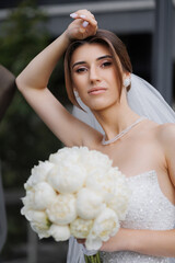 Bride with elegant bouquet poses confidently outdoors before the ceremony