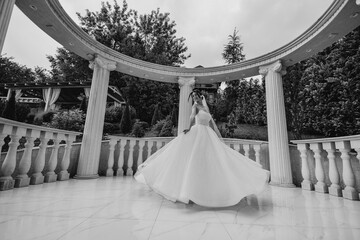 Bride twirls in elegant dress under architectural columns during outdoor wedding ceremony