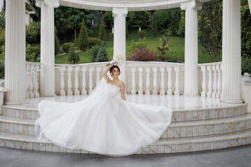 Elegant bride poses gracefully on a marble stage in a serene garden setting