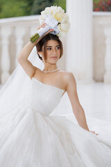 Beautiful bride holding bouquet in elegant wedding dress at outdoor venue during daytime