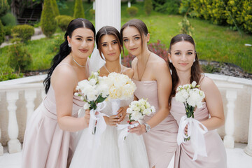 Bridesmaids pose together in an outdoor garden setting during a wedding celebration