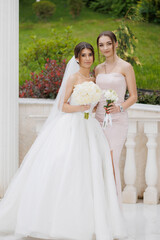 Two women smiling together at an outdoor wedding venue during a daytime celebration