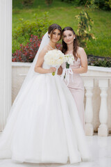 Bridesmaid and bride celebrate wedding day at outdoor venue with beautiful flowers