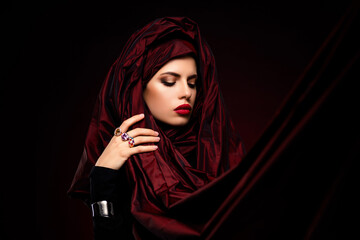 Portrait of a female model draped in rich red fabric, showcasing elegance and luxury in a striking...