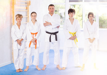 Portrait of male karate or judo coach with her students children in the gym