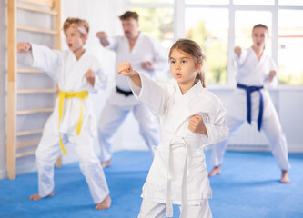Children with parents in kimono standing in fight stance during group karate training © JackF