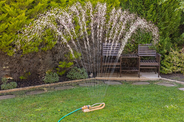 Garden Sprinkler Watering a Lush Backyard Lawn