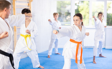 In gym, certified master coach conducts karate kata lesson with children boys girls team students...