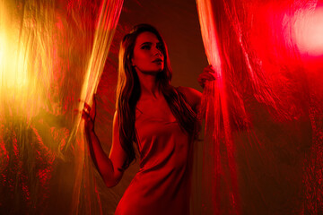 Portrait of a graceful woman in studio minimalistic fashion style, illuminated by vibrant red and yellow lighting