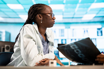 African american physician consulting a female patient in a facility office, reviewing diagnostics...