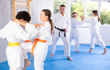 Children students athletes at Academy of martial Arts practice aikido and fight opponents in pairs....
