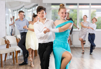 Teen guy and girl perform movements and dance hustle in pairs under guidance of woman coach....