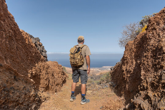 Hiker Pauses to Admire the Expansive Coastal View from a Mountain Path. Vacation Concept