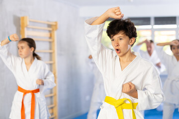 Obraz premium Kata karate teacher conducts classes and performs movements and fighting techniques together with boys and girls students to prepare them for competitions.