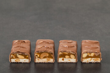 Chocolate Candy bar. Nougat, caramel with peanuts, in milk chocolat. Dark background. Copy space