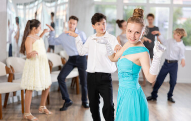 Teen girl in elegant evening dress dances incendiary twist with boy partner during choreography...