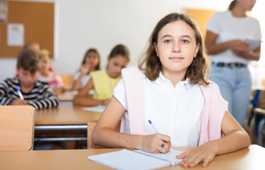 Portrait of schoolgirl who writing exercises at lesson in school