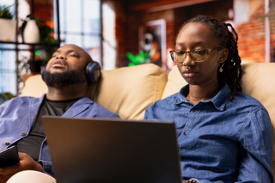 African american woman multitasking on a laptop in her stylish loft, fully connected to the internet while managing her freelance tasks and remote responsibilities. Browsing web at her home.