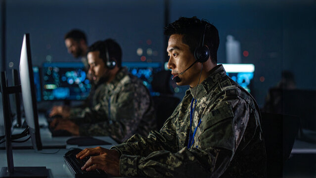 Dedicated individuals working in a dark room, focused on computers. The scene evokes professionalism and concentration in a technologically advanced environment.