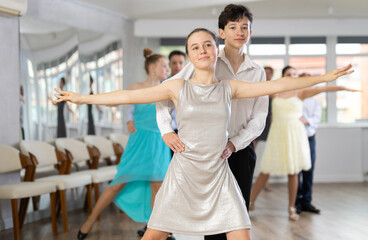 Teen guy and girl perform movements and dance hustle in pairs under guidance of woman coach....