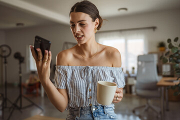 smiling woman take a self portrait on mobile phone hold coffee cup